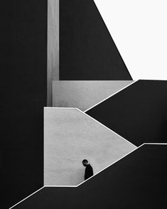 black and white photograph of a man standing in the middle of an abstractly designed building