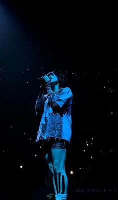 a woman standing on top of a stage with her hands in her mouth while singing into a microphone