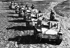 a line of tanks driving down a dirt road