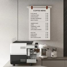 a menu hanging on the wall above a coffee machine and espresso machine in front of it