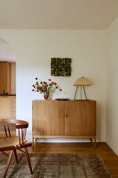 a wooden cabinet sitting in the middle of a living room next to a table and chairs