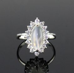 This Sterling Silver Ring features an Elegant Art With Natural Moonstone Gemstone. The cavity is made from genuine solid 925 sterling silver and stamped as S925. This Jewelry is Lead free and Rhodium Plated to keep polish long time and Scratches free. ITEM DESCRIPTION Item Code: JARG337/12 Metal: 925/92.5 Sterling Silver Gemstone: Genuine Natural Moonstone Cabochon Gemstone Shape: Marquise Gemstone Size: 6 X 12 MM Ring Length: 18 MM Ring width: 11 MM Second Stone: Cubic Zirconia Weight: 3.2 gm a Silver Crystal Halo Ring As Gift, Silver Halo Crystal Ring As A Gift, Silver Halo Crystal Ring Fine Jewelry, Formal Silver Moonstone Ring With Center Stone, Silver Moonstone Ring With Accent Stones, Silver Moonstone Ring With Halo Setting For Wedding, Silver Opal Ring With Halo For Anniversary, Silver Opal Ring With Halo Setting In Sterling Silver, Silver Rings With Halo Setting And Moonstone