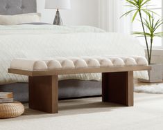 a bed sitting next to a wooden bench on top of a white carpeted floor