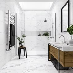 a bathroom with white marble walls and flooring, along with a wooden vanity sink