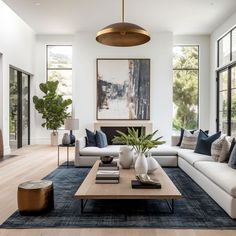 a living room with white couches and blue rugs in front of large windows