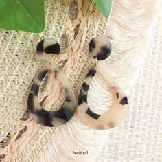 a pair of tortoise shell hoop earrings on top of a piece of fabric