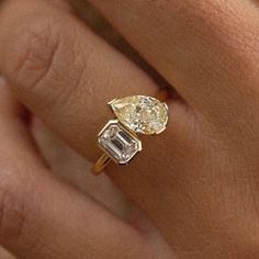 a woman's hand with a yellow and white diamond ring on top of her finger