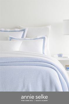 an image of a bed with white and blue sheets