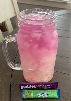 a pink drink in a mason jar next to a purple candy bar