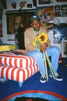 a man sitting on top of a bed holding a bouquet of sunflowers in his hand