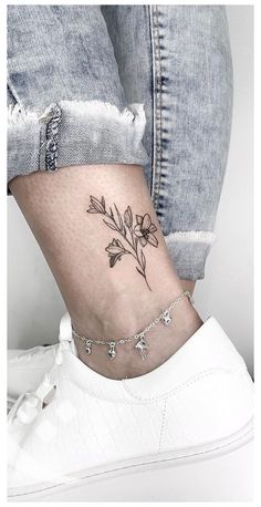 a woman's ankle with a small flower tattoo on her left side ribcage