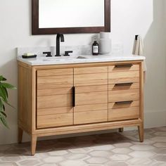 a bathroom vanity with a mirror above it and a plant in the corner next to it