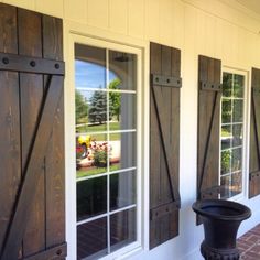 the side of a house that has shutters on both sides and an iron urn in front of it