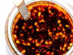 a glass jar filled with lots of food on top of a white countertop next to a metal spoon