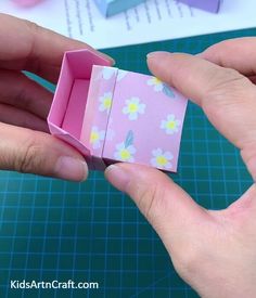 someone is holding an origami box with flowers on it and the paper inside