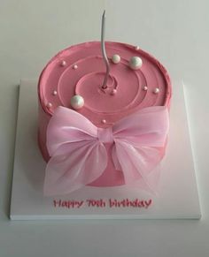 a pink birthday cake decorated with pearls and a bow