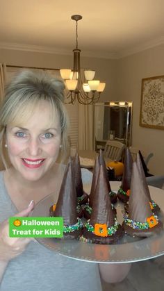 a woman is holding a tray with chocolate cones on it that have candy in them