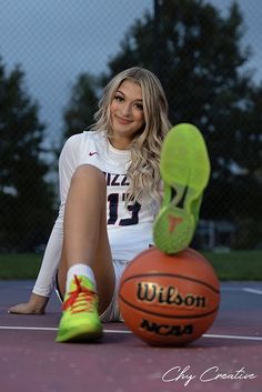 a woman sitting on the ground next to a basketball ball and shoe in front of her