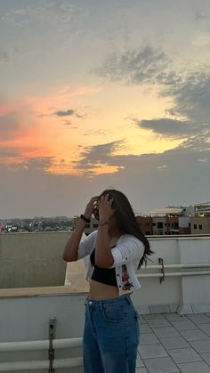 a woman standing on top of a roof looking into the sky with her hands in her eyes