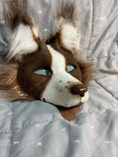 a stuffed animal head laying on top of a bed covered in white and brown sheets