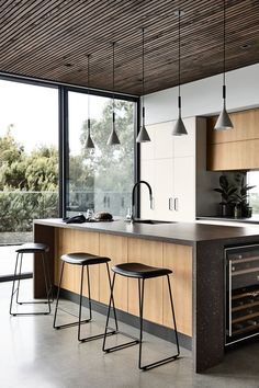 a kitchen with two stools in front of the counter and an open wine cooler