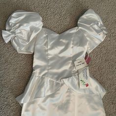 a white dress is laying on the floor and has a tag in it's pocket