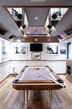 a pool table in the middle of a room with pictures on the wall above it