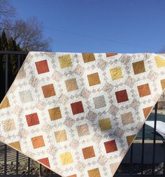 a person holding up a quilt in front of a fence