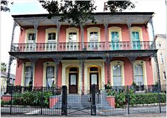 a pink and yellow house with wrought iron fence around it's front entrance area