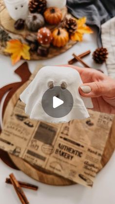 someone is holding up a paper towel with an image of a ghost on it and some pumpkins in the background