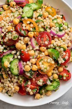 a white bowl filled with corn, tomatoes and cucumber on top of a table