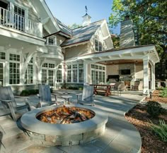 a fire pit sitting in the middle of a patio next to a large white house