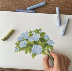 a person is drawing flowers on paper with crayons