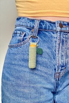 a person wearing blue jeans with a cell phone charm attached to their waist and the back pocket