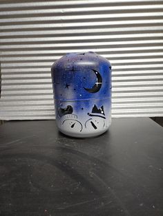 a blue and white vase sitting on top of a black table next to a window