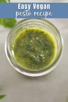 an easy vegan pesto recipe in a small glass jar with basil leaves around it