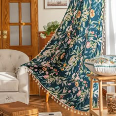 a living room with a chair and a blue floral blanket hanging from the ceiling next to a window