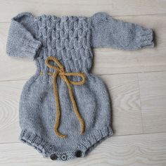 a blue knitted baby romper with a yellow ribbon on the front and bottom