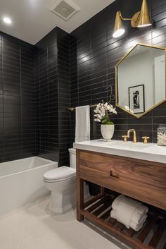 a white toilet sitting next to a bath tub under a bathroom mirror above a sink