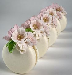 four white vases with pink flowers in them