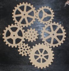 four wooden gears sitting on top of a black table next to each other with holes in them