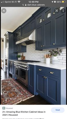 a kitchen with dark blue cabinets and white subway backsplash, gold pulls on the hood