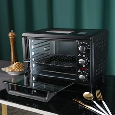 a black toaster oven sitting on top of a counter next to utensils