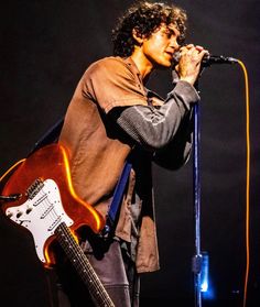 a man holding a guitar and singing into a microphone