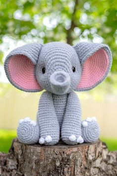 a crocheted elephant sitting on top of a tree stump