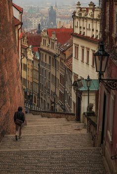 a person walking up some stairs in an old city with buildings on the other side