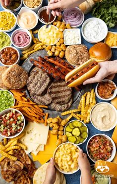 people are eating different types of food on the table, including burgers and hotdogs