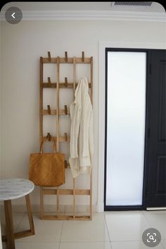 a coat rack, table and chair in a room with white tiles on the floor