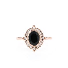 an oval black and white diamond ring on a white background with the center stone surrounded by small diamonds