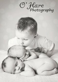 a black and white photo of two babys cuddling on top of each other